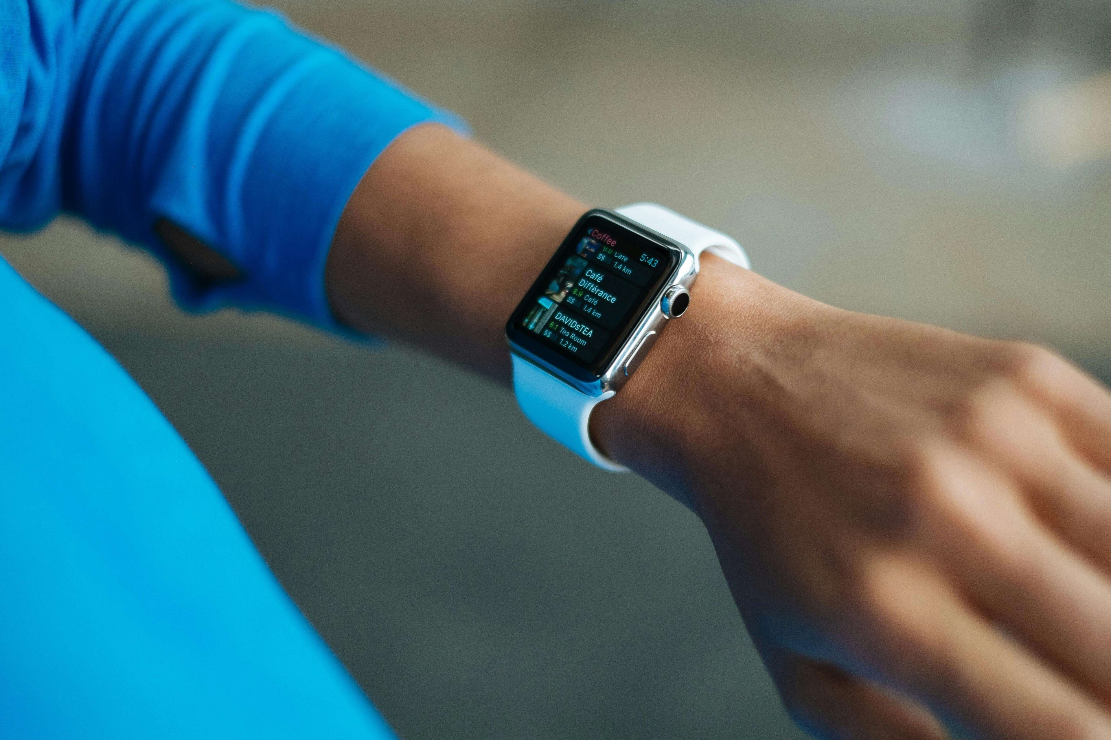 Close-up of a hand wearing a smartwatch displaying notifications, set against a blurred background.