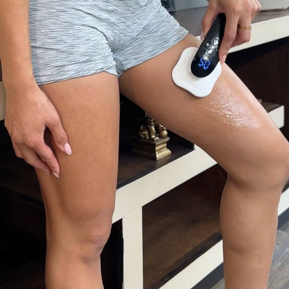 Woman using EMS ultrasonic fat removal machine on her thigh for body shaping and weight loss.